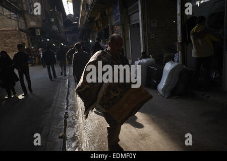 Tehran, Iran. Il 7 gennaio, 2015. 7 gennaio 2015 - Teheran, Iran - Un lavoratore iraniano che porta una mano persiano tappeto tessuto a Tehran nel tappetino del Bazaar. Morteza Nikoubazl/ZUMAPRESS © Morteza Nikoubazl/ZUMA filo/Alamy Live News Foto Stock