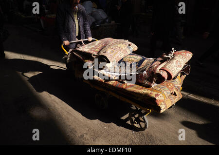 Tehran, Iran. Il 7 gennaio, 2015. 7 gennaio 2015 - Teheran, Iran - Un lavoratore iraniano che trasportano il persiano a mano tappeti tessuti con un carrello a Teheran il tappeto Bazaar. Morteza Nikoubazl/ZUMAPRESS © Morteza Nikoubazl/ZUMA filo/Alamy Live News Foto Stock