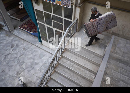 Tehran, Iran. Il 7 gennaio, 2015. 7 gennaio 2015 - Teheran, Iran - Un lavoratore iraniano che porta una mano persiano tappeti tessuti a Teheran il tappeto Bazaar. Morteza Nikoubazl/ZUMAPRESS © Morteza Nikoubazl/ZUMA filo/Alamy Live News Foto Stock