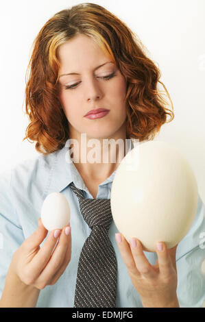 Donna che guarda in corrispondenza di due diverse dimensioni di uova Foto Stock