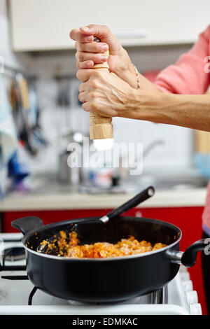 Donna cook pepe di macinazione sopra le lasagne ricetta in padella Foto Stock