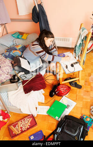 Adolescente a studiare nella sua stanza disordinati Foto Stock