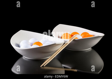 Due ceramiche bianche bocce con palline da golf sul tavolo di vetro Foto Stock