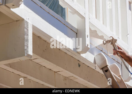 Pittore di casa indossando la protezione del viso verniciatura a spruzzo di un ponte di una casa. Foto Stock