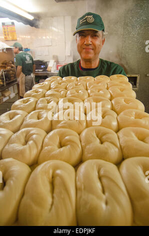 Bollitore-boiled bagel sono trasportati verso il forno per la sua fase finale di preparazione alla New York City's ess-a-Bagel. Foto Stock