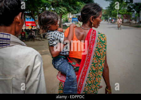 Una donna trasporta il suo bambino mentre sta camminando sulla strada principale di Bodh Gaya in Bihar, India. Foto Stock