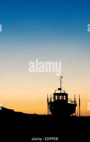 Barca da pesca sulla terraferma a sunrise nel porto di Lindisfarne, Isola Santa, Northumberland, Inghilterra. Silhouette Foto Stock