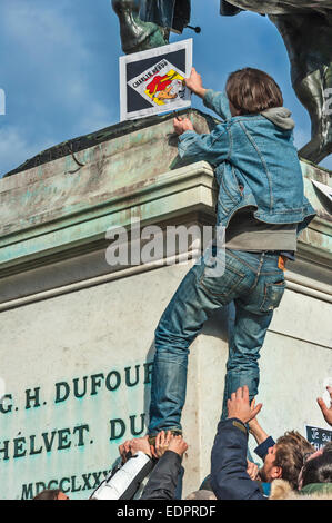 Ginevra, Svizzera. 8 gennaio 2015. Un giornalista salendo su una statua di eroe svizzero Generale Dufour per collocare un poster durante una vigilia di Ginevra's Place de Neuve per mostrare solidarietà con le vittime dell attentato contro Charlie Hebdo in Parigi Credito: Alistair Scott/Alamy Live News Foto Stock