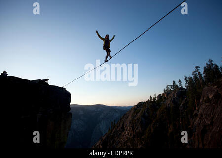 Silhouette di professional highliner Hayley Ashburn a piedi una highline sopra la valle di Yosemite piano al punto Taft Foto Stock