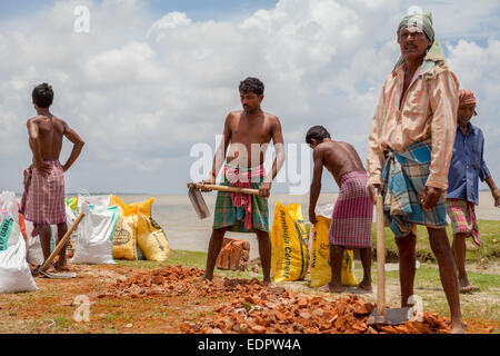 Lavoratori che riempiono sacchi con pezzi di mattoni per il progetto di controllo di erosione del fiume sulla riva del fiume Rupnarayan a Tamluk, Bengala Occidentale, India. Foto Stock