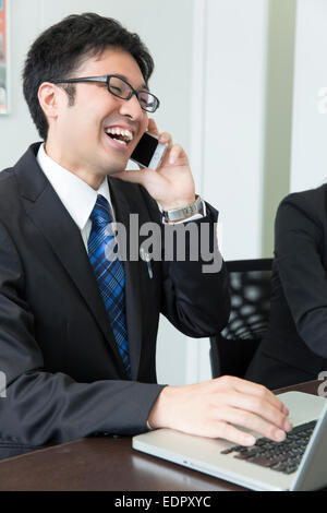 Imprenditore parlando al telefono cellulare e uso del computer Foto Stock