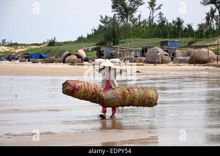 Pescatore femmina cestini di bilanciamento a beach nel sud Vietnam Mui ne Foto Stock