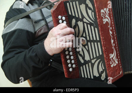 Uomo seduto a giocare un rosso di fisarmonica vecchio Foto Stock