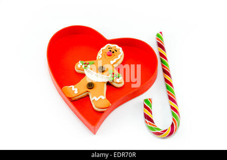 Gingerbread e un candy cane in un cuore scatola sagomata isolata su sfondo bianco Foto Stock