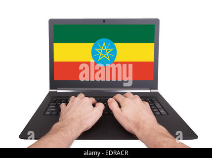 Mani lavorando su laptop che mostra sullo schermo la bandiera di Etiopia Foto Stock