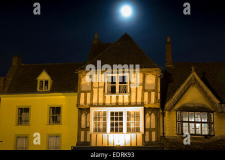 Luna piena che brilla sulla antica architettura medievale lungo Burford High Street di notte, i Cotswolds Foto Stock