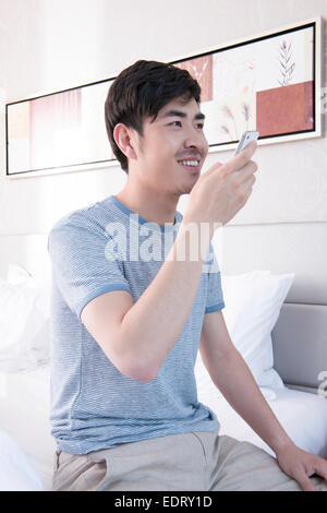 Giovane uomo invio di messaggio vocale nel letto Foto Stock
