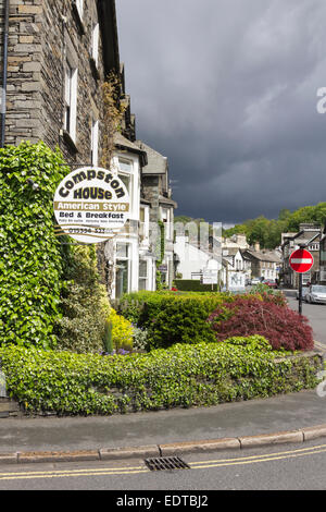 Lake District Pensioni a Ambleside, Cumbria. Dark le nuvole minacciano pioggia sopra il fells oltre la città. Foto Stock