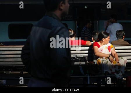 Una donna passeggero è in attesa per l'orario di partenza come lei è seduta su una panchina sulla piattaforma passeggeri a Nuova Delhi Stazione ferroviaria a Delhi, India. Foto Stock