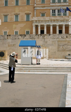 Turistica prendendo le foto del parlamento greco e evzone guardia con uniforme tradizionale presso la tomba del milite ignoto. Foto Stock