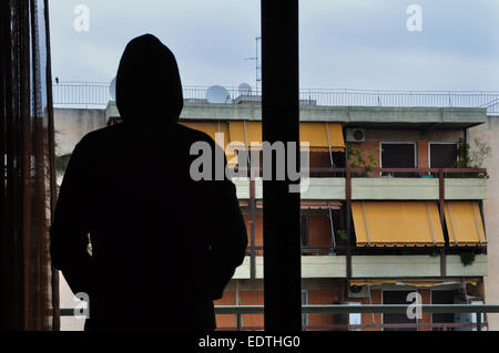 Uomo che guarda gli edifici della città attraverso la finestra. Foto Stock