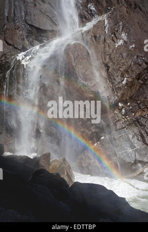 Acqua, arcobaleno e frazil ghiaccio in corrispondenza della base inferiore di Yosemite Falls nel Parco Nazionale di Yosemite Foto Stock