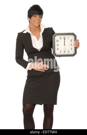 Business donna tenendo un orologio che legge ore 12 e gesti al suo stomaco. Può rappresentare la fame durante la pausa pranzo. Foto Stock