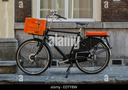 Una bicicletta vintage con accenti di colore arancione è parcheggiato su un marciapiede di strada nei Paesi Bassi Foto Stock