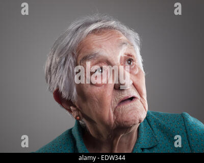Donna anziana ritratto in uno studio shot. Vecchia donna è guardando verso l'alto. Foto Stock