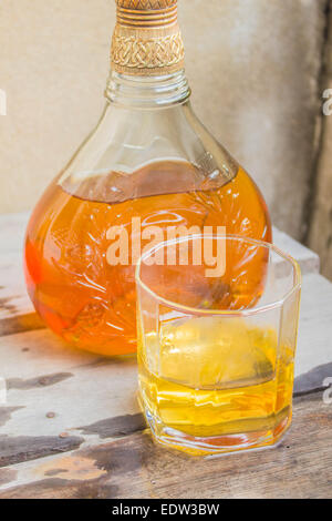 Bicchiere di whiskey versato sul pavimento in legno. Foto Stock