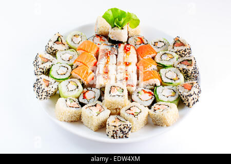 Sushi rullo impostato su un piatto bianco. Diversi piatti giapponesi. Gamberetti, sesamo, salmone, anguilla. Messa a fuoco selettiva. Foto Stock