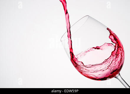 Versando il vino in un vetro di composizione diagonale e sfondo bianco Foto Stock