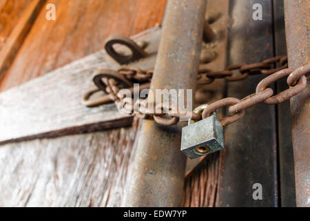 Catena arrugginita e master il tasto di bloccaggio della porta di legno Foto Stock