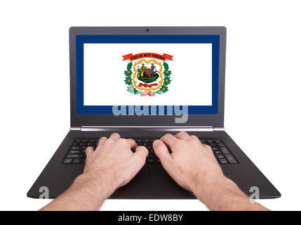 Mani lavorando su laptop che mostra sullo schermo la bandiera della West Virginia Foto Stock