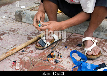 Un uomo che lavora come scavenger elimina piccole schede a circuito elettronico da piccolo apparecchio tappi in libertà Park a Phnom Penh, Foto Stock