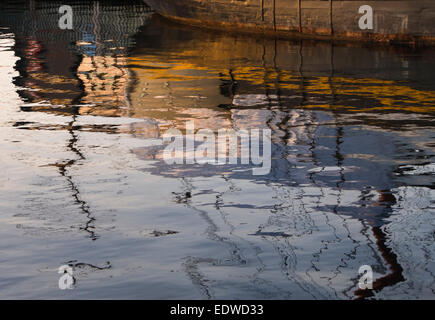 Golden sole invernale impostazione, riflessa da un molo e barche sulle acque del porto di Oslo Norvegia Foto Stock