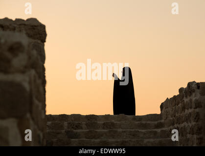 Donna musulmana prendendo foto e stagliano tramonto al Bahrain Fort vicino a Manama al Seef, Bahrain Foto Stock