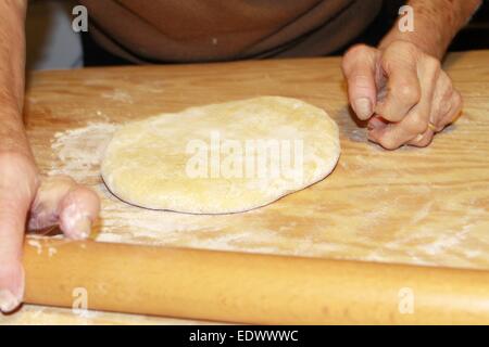 Impasto essendo appiattito su un tagliere di legno Foto Stock