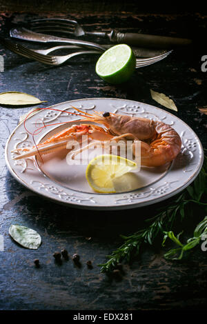 La cottura di langoustine con il limone sulla piastra vintage sulla tavola nera Foto Stock