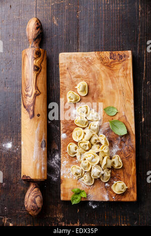 In casa materie i tortellini e le foglie di basilico scuro su sfondo di legno Foto Stock