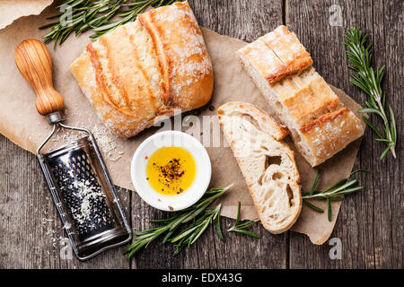 Fette di pane Ciabatta e olio extra vergine di oliva su sfondo di legno Foto Stock