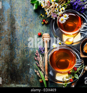 Il tè alle erbe con miele e frutti di bosco e fiori su sfondo di legno Foto Stock