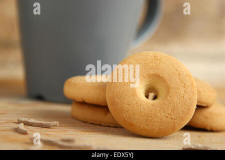 Round cookie disposti in pila vicino a una tazza di latte con bastoncini di crusca su una tavola di legno Foto Stock