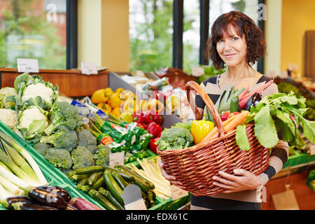 Anziani donna sorridente acquistare verdure fresche in un supermercato Foto Stock