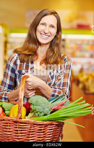 Attraente donna anziana che trasportano carrello pieno di verdure fresche Foto Stock