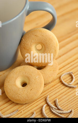 Round cookie disposti in pila vicino a una tazza di latte con bastoncini di crusca su una tavola di legno Foto Stock