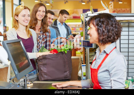 Donna con negozi di generi alimentari in attesa in fila al supermercato checkout Foto Stock