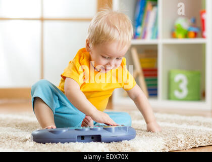 Felice capretto piccolo ragazzo suonare il pianoforte giocattolo Foto Stock