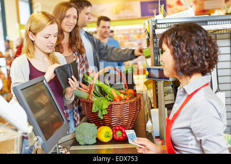 Giovane donna in coda al supermercato è mancante il denaro per il pagamento Foto Stock