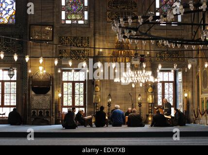 Gli uomini la lettura di Corano e pregando, Yeni Cami (Nuova Moschea), Eminonu, Istanbul, Turchia. Foto Stock